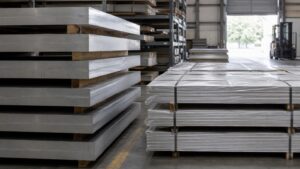 aluminum sheet vs plate - stacked aluminum plate and sheet bundles on wooden pallets in an export warehouse showing the thickness difference